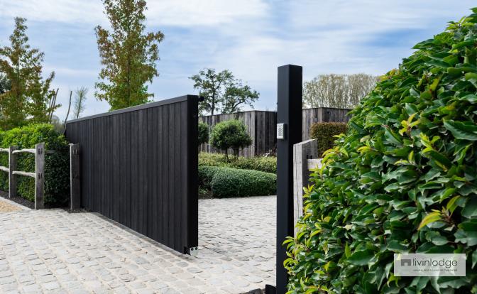 The black sliding gate blends with the surrounding vegetation