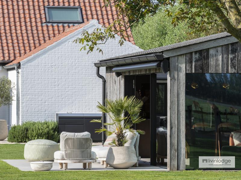 Decking with lounge area adjoining a garden room in Damme