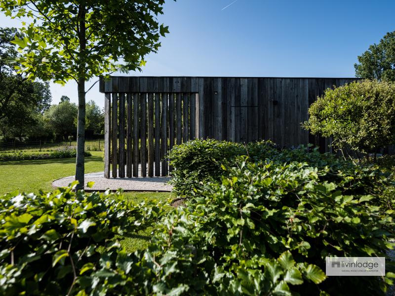 The barnwood outbuilding blends harmoniously into the natural surroundings