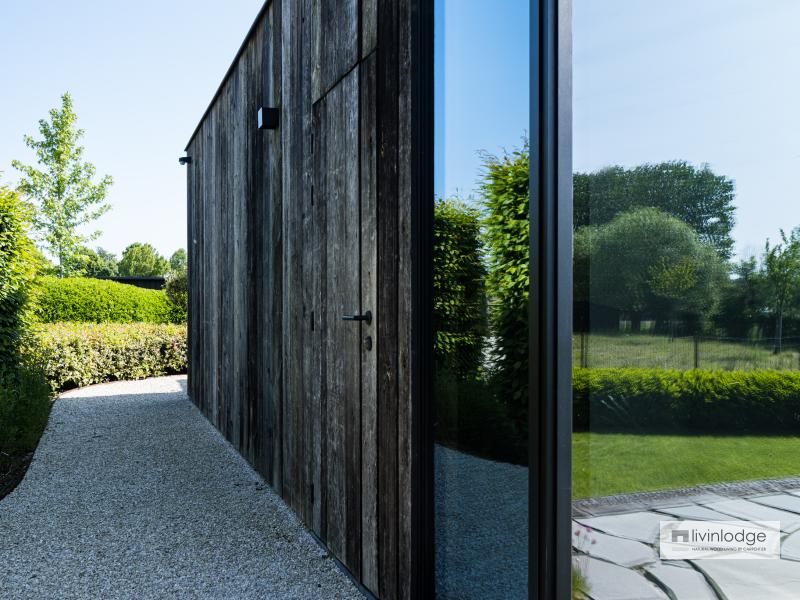 A barnwood door is beautifully integrated into the exterior wall of the outbuilding